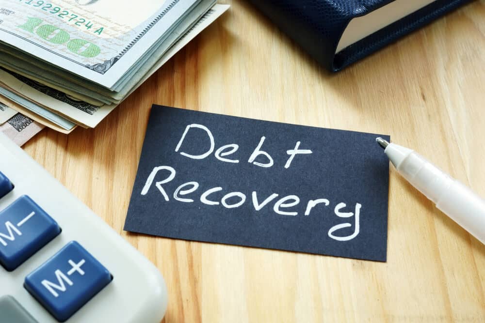 Australian business owner reviewing unpaid invoices and debt recovery paperwork, illustrating commercial debt collection and legal recovery strategies in Australia for 2026